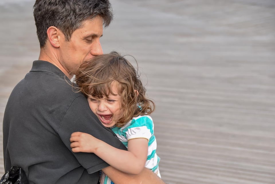 distraught little girl, cries, father's lap, tantrums