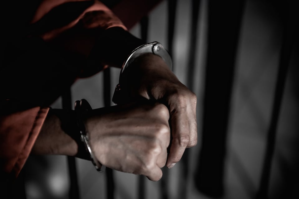 Hands of man in jail with handcuffs