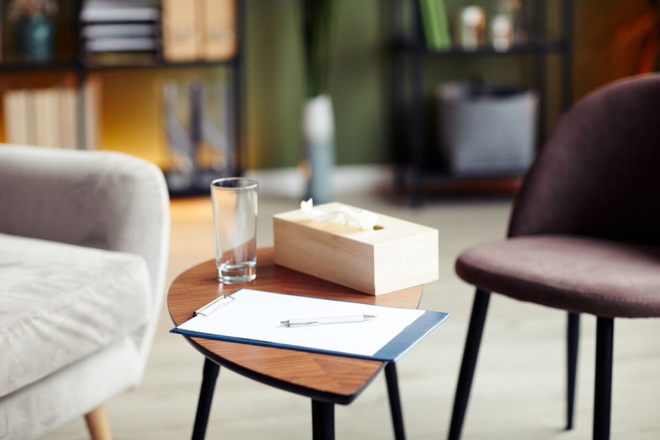 Mesa de consultorio de un psicólogo con vaso, pañuelos y tabla para escribir