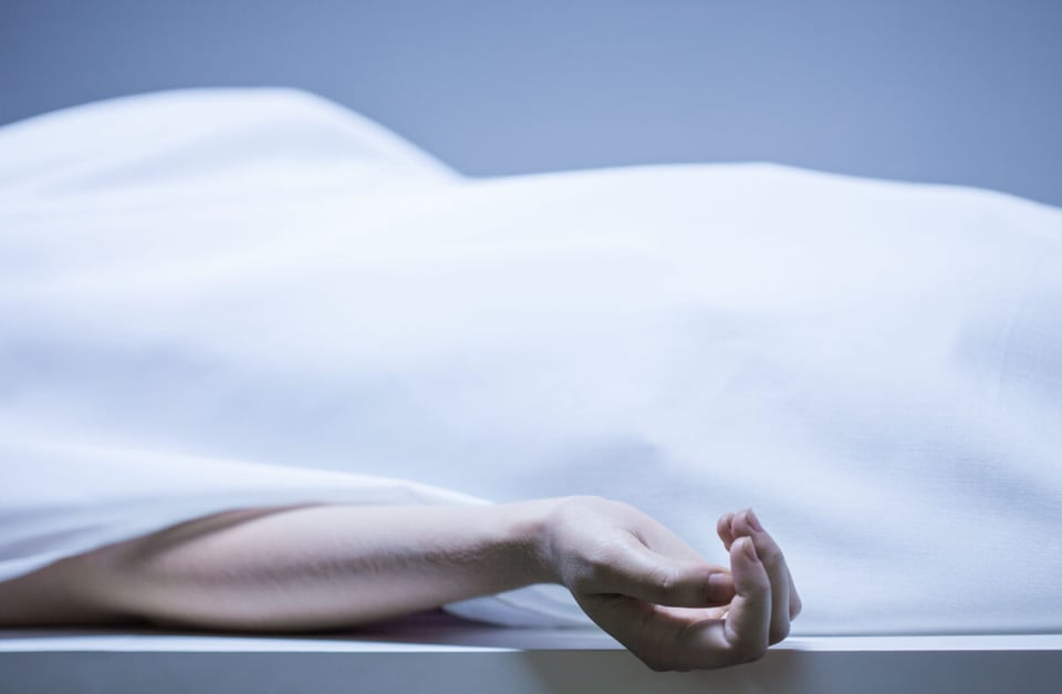 El cadáver de un hombre asesinado tapado con mano visible