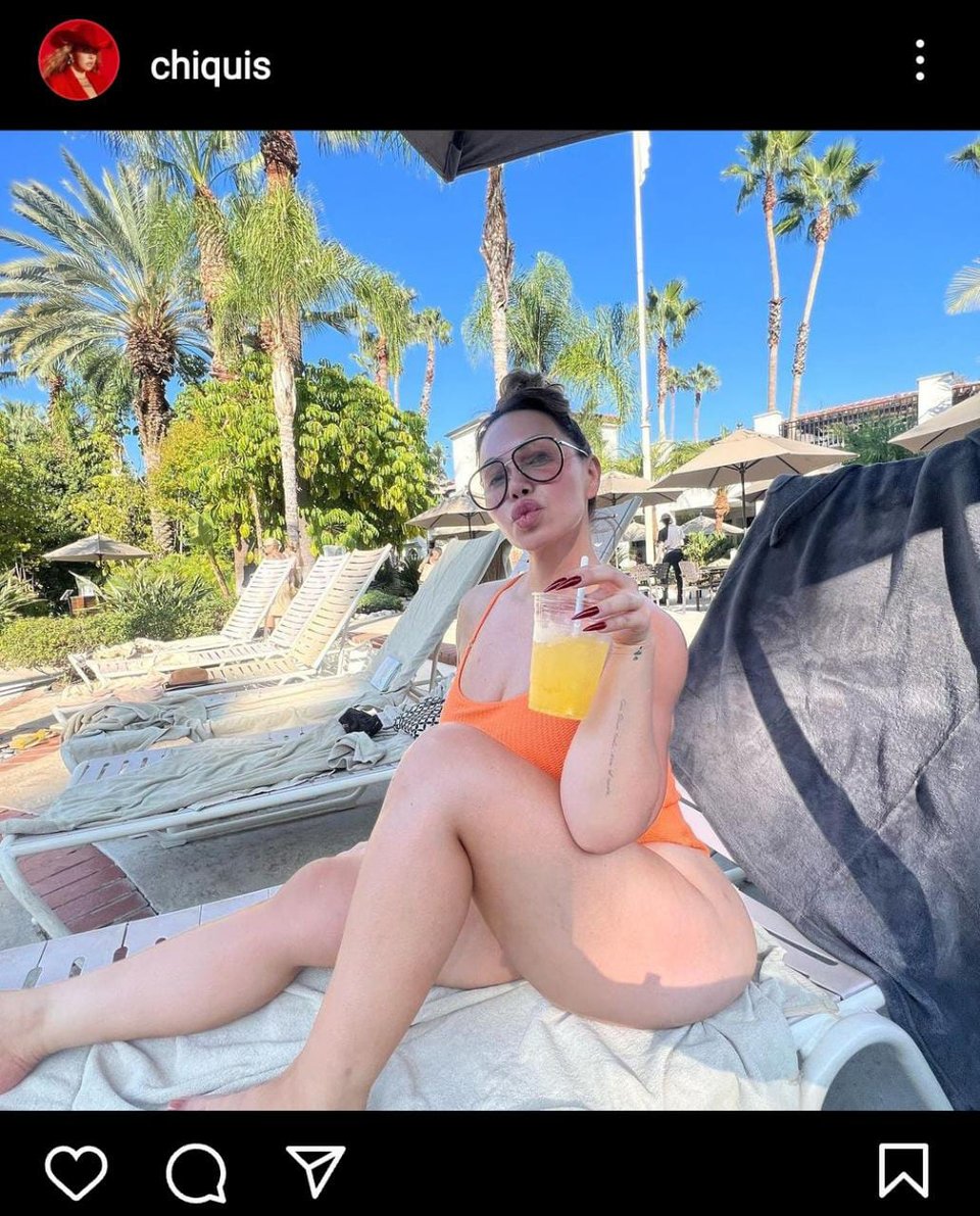 Relaxed, Chiquis Rivera wears an orange swimsuit