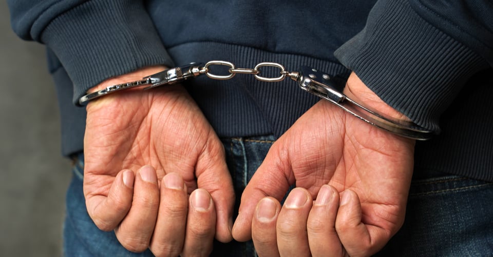 Hands of an arrested murderer with handcuffs
