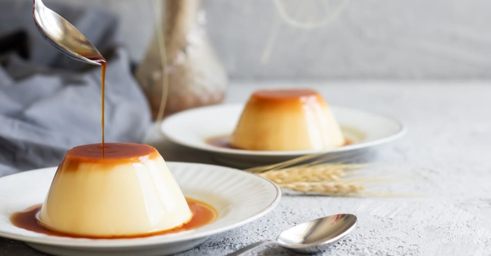 A spoon pouring a sweet liquid onto a flan