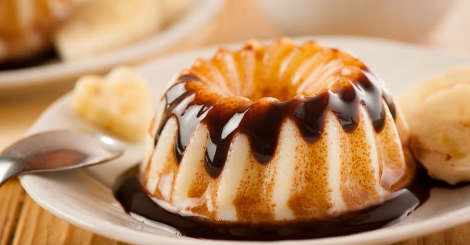 A flan with a spoon on the side with spilled candy